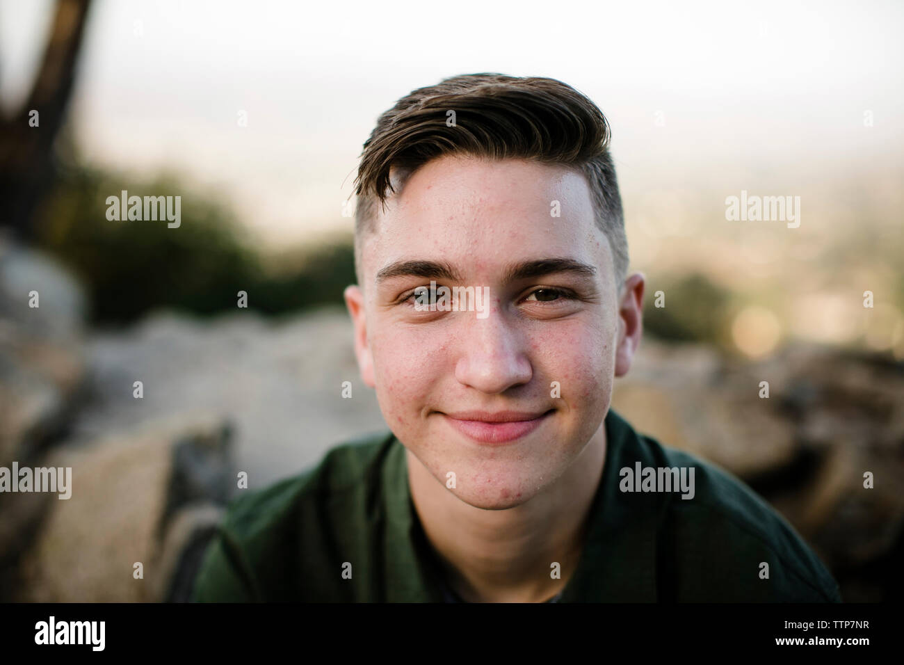 Close-up portrait of smiling handsome man sitting contre sky at park Banque D'Images