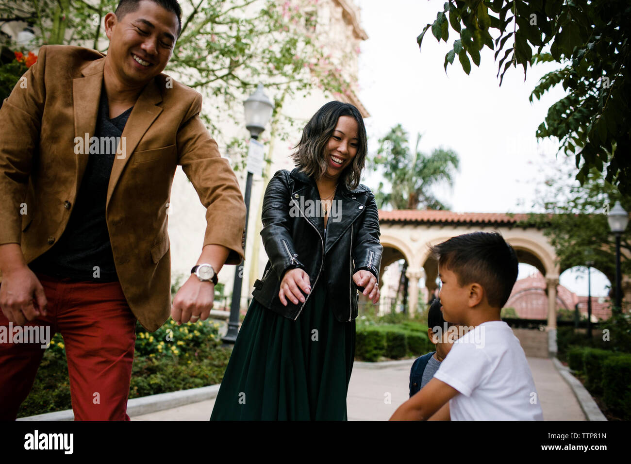 Heureux parents danse avec fils en se tenant sur le trottoir contre ciel à Balboa Park Banque D'Images