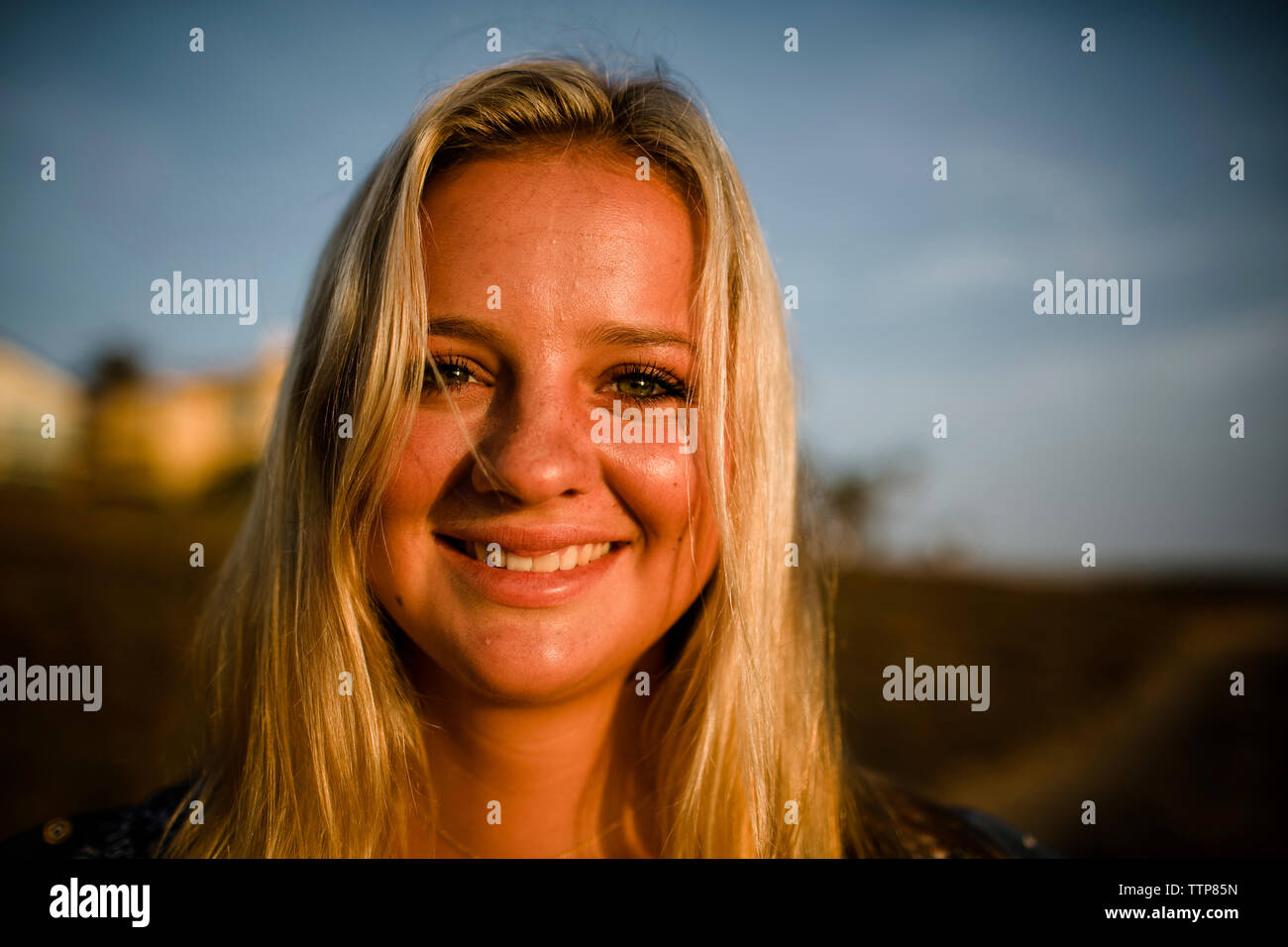 Close-up portrait of smiling woman with Blonde hair comité permanent à la sky pendant le coucher du soleil Banque D'Images