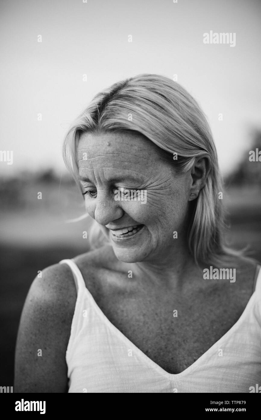 Close-up of happy woman tout en se tenant à la sky pendant le coucher du soleil Banque D'Images