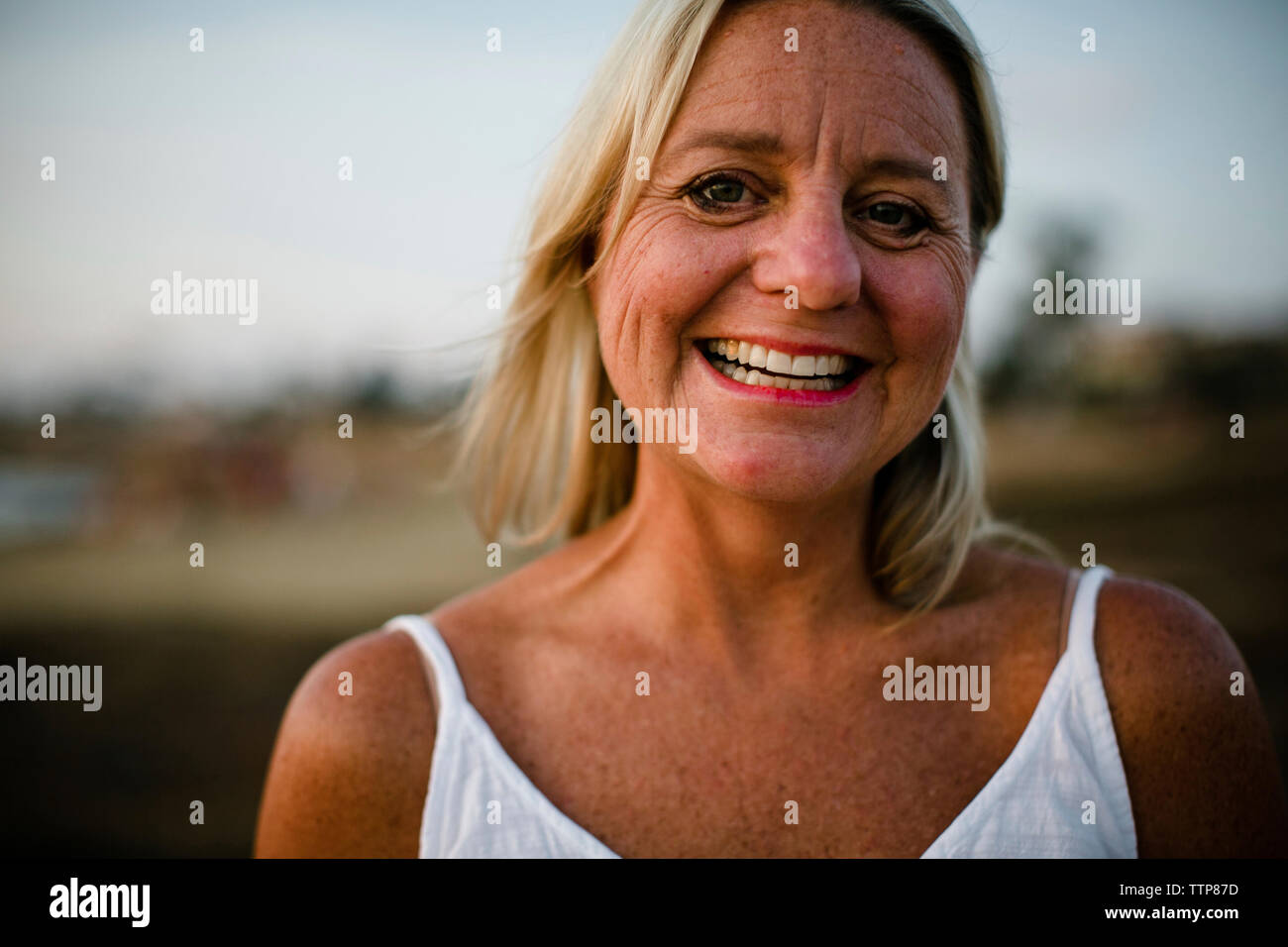 Close-up portrait of happy woman standing at beach contre le ciel au coucher du soleil Banque D'Images