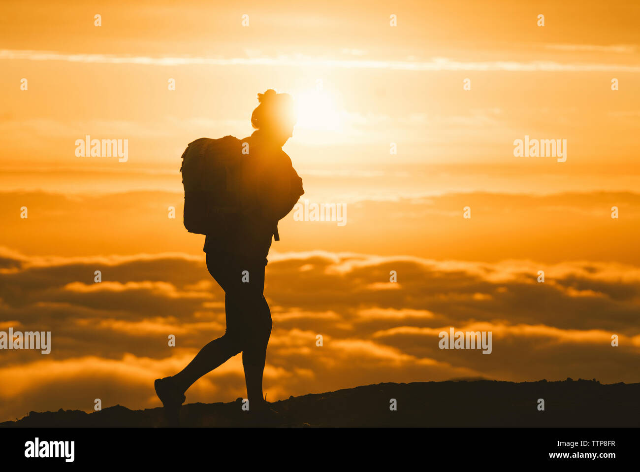 Silhouette female hiker walking on mountain pendant le coucher du soleil Banque D'Images