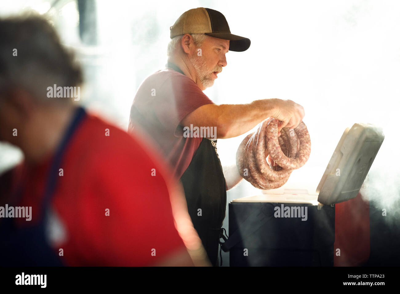 Man making saucisse avec un collègue dans la cuisine Banque D'Images