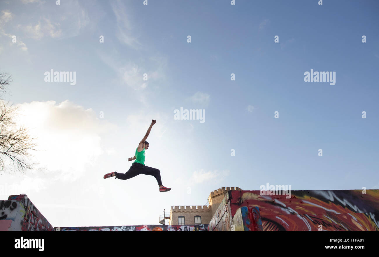 Low angle view of stunt man jumping over bâtiments contre sky Banque D'Images