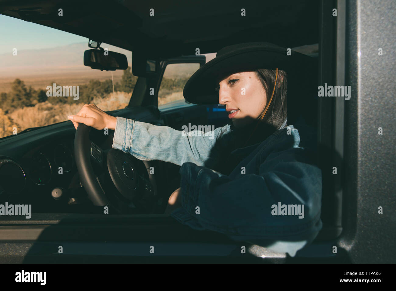 Close-up of young woman sitting on du conducteur pour véhicule hors route dans le desert pendant journée ensoleillée Banque D'Images