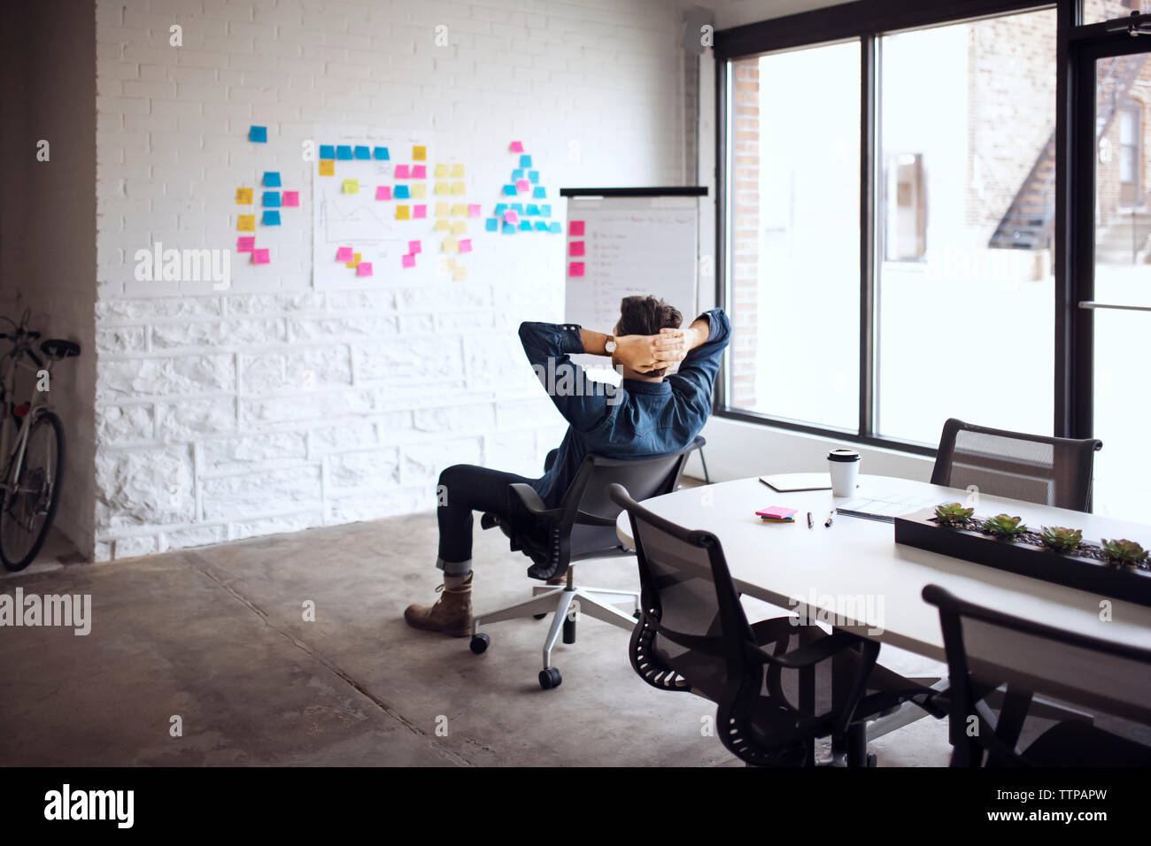 homme d'affaires assis sur la chaise avec les mains derrière la tête dans le bureau créatif Banque D'Images