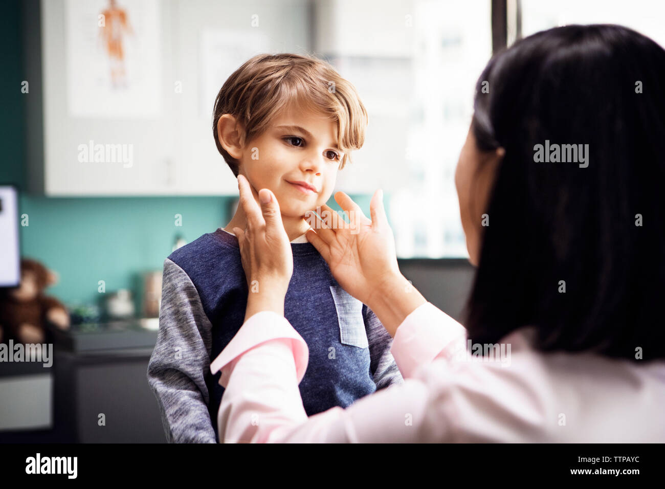 Vue arrière du female doctor examining boy's glandes dans clinic Banque D'Images