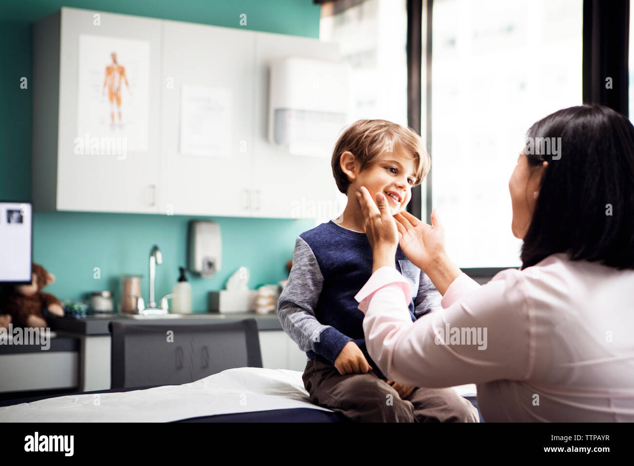 Femme médecin examinant les glandes du garçon en clinique Banque D'Images