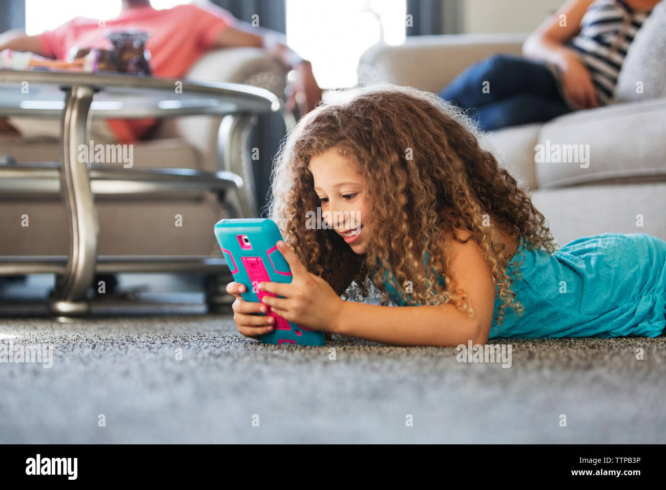 Happy girl playing handheld video game en position couchée sur un tapis à la maison Banque D'Images
