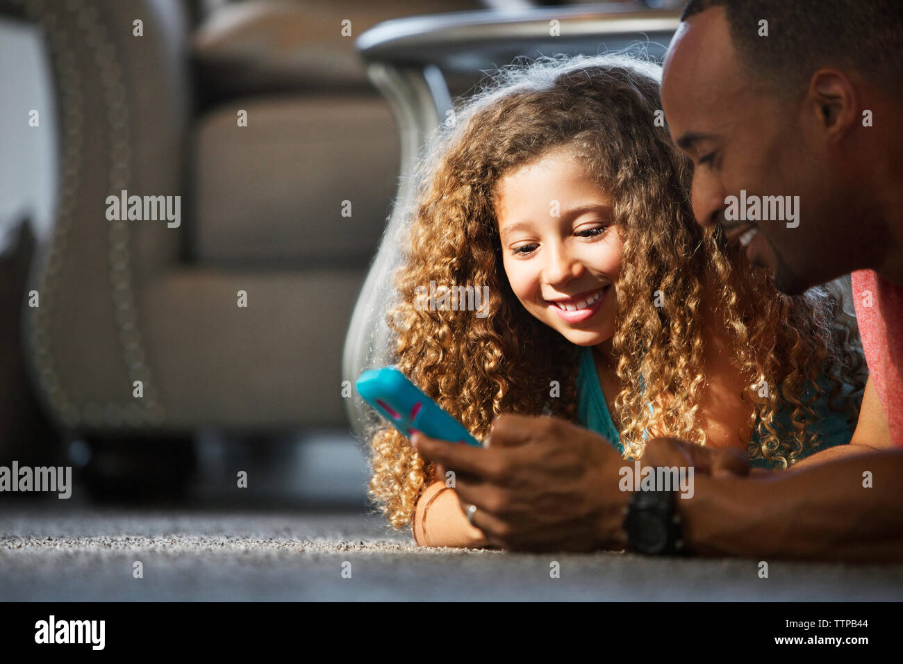 Heureux père et fille jouer jeu vidéo tout en étant allongé sur un tapis à la maison Banque D'Images