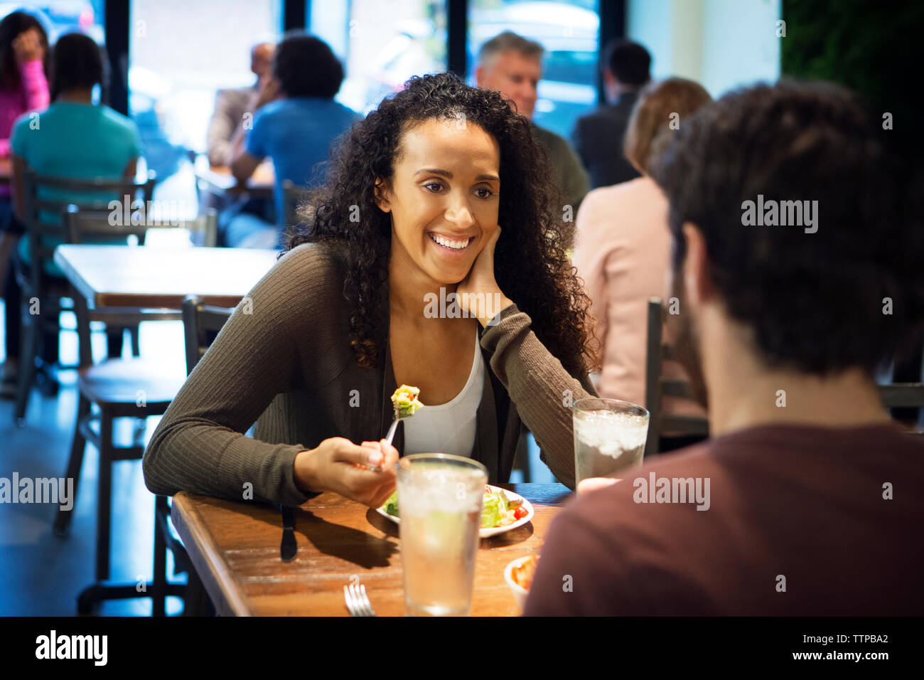 Femme assise avec l'homme ayant la cuisine du restaurant Banque D'Images