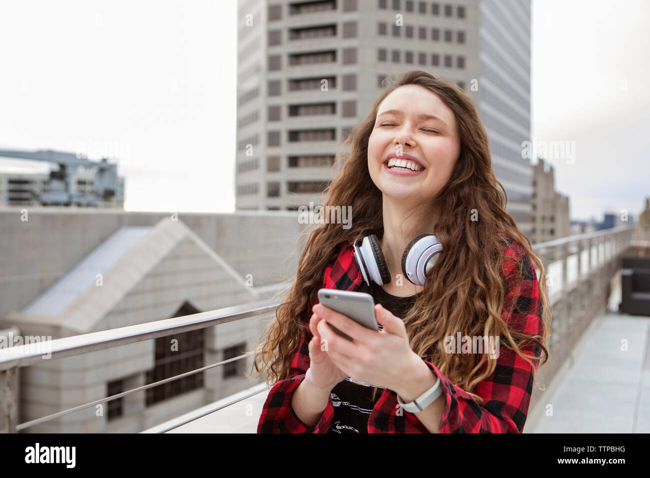 Cheerful woman using smart phone en étant debout à Terrace cafe Banque D'Images