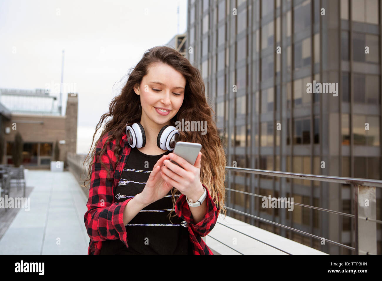 Young woman using smart phone en marchant à Terrace cafe Banque D'Images