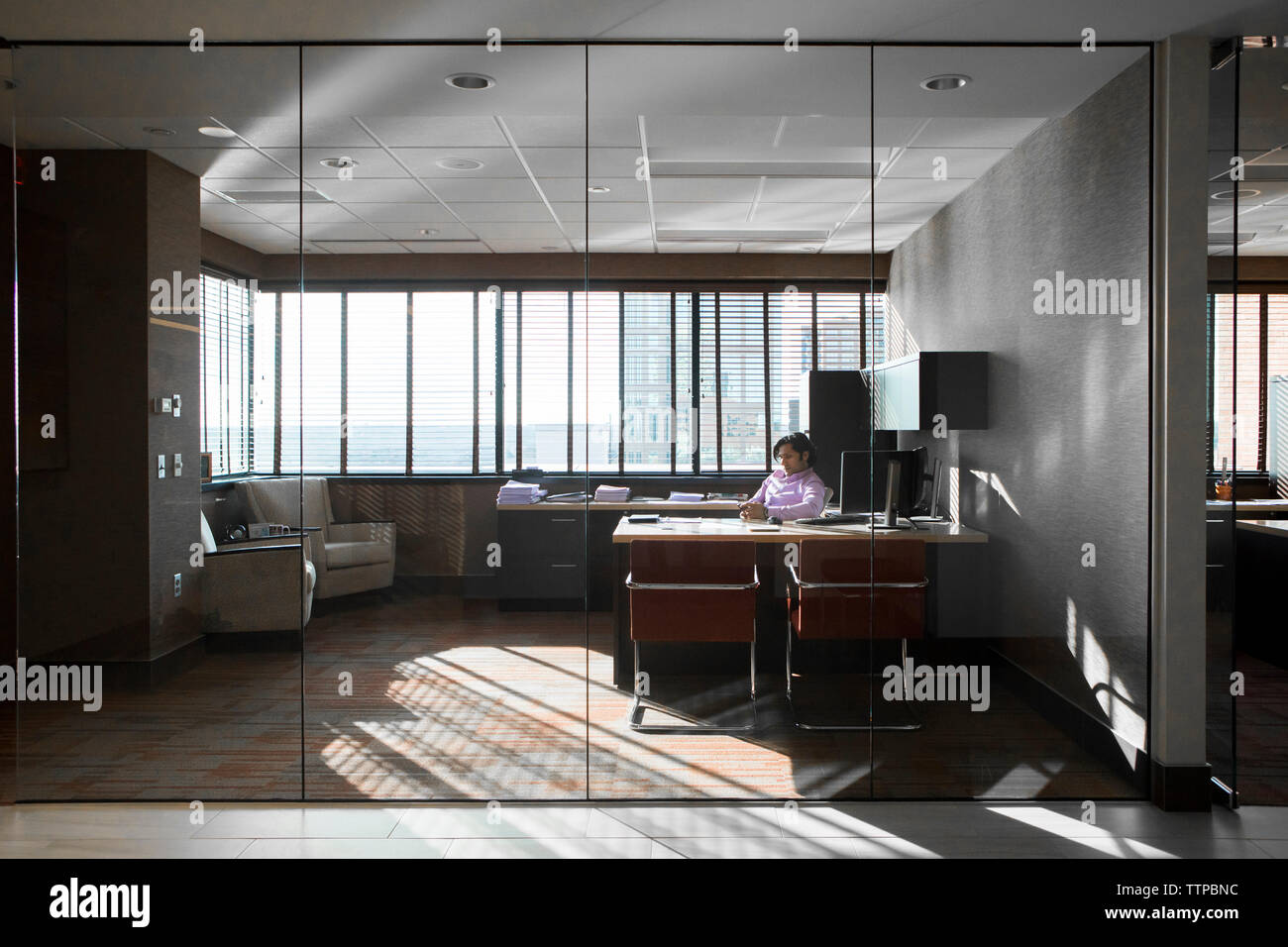 homme d'affaires utilisant le téléphone portable au bureau dans le bureau vu à travers le verre Banque D'Images