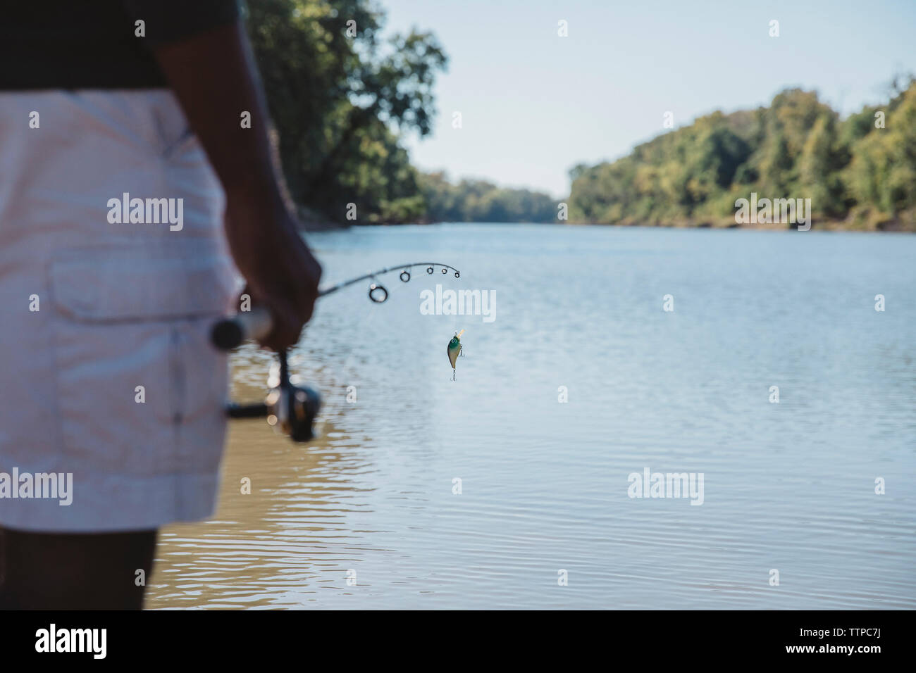 Portrait de l'homme tenant la canne à pêche en position debout dans le lac contre le ciel clair Banque D'Images