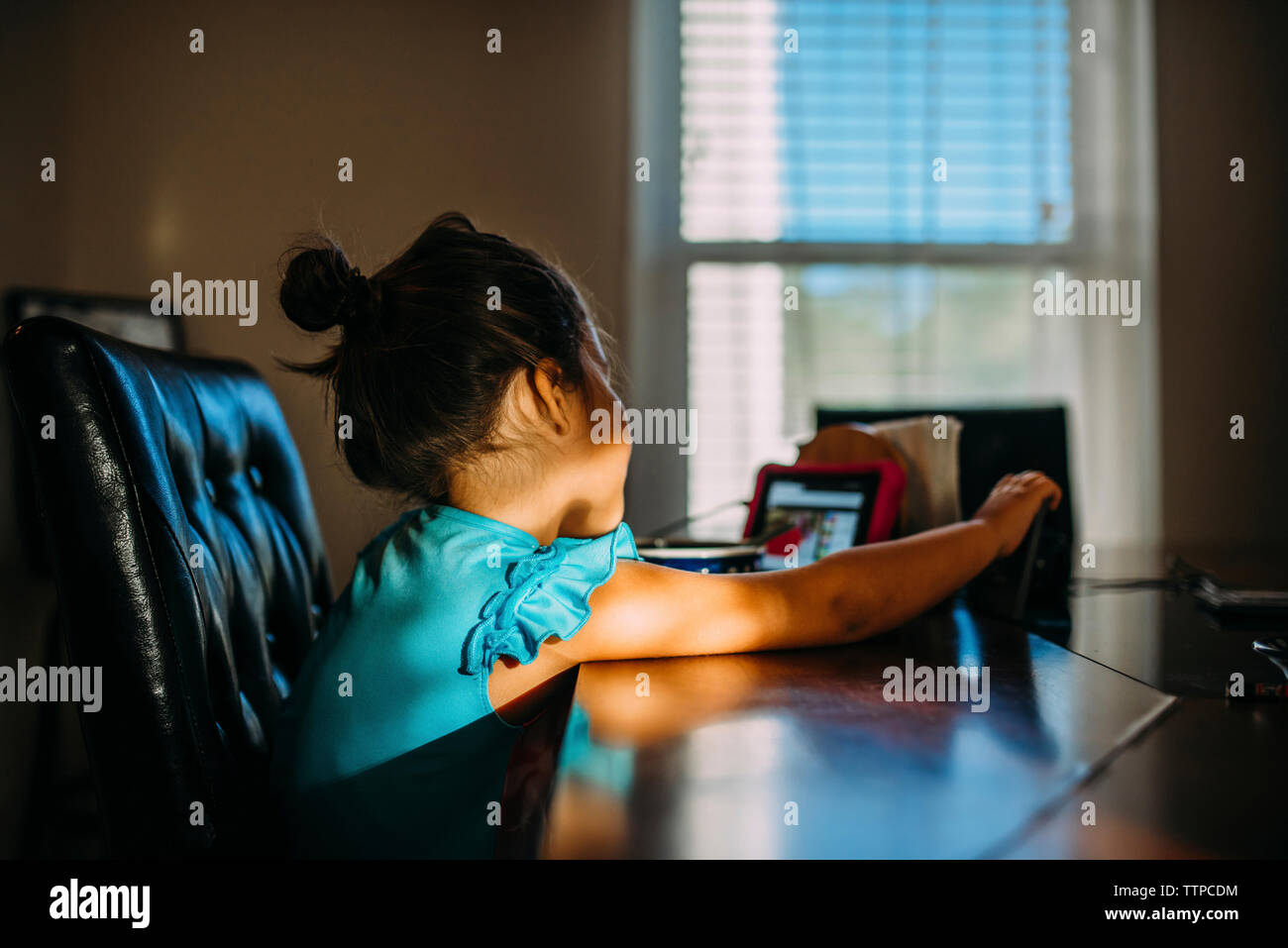 Vue de côté de girl jeu vidéo tout en étant assis à table Banque D'Images