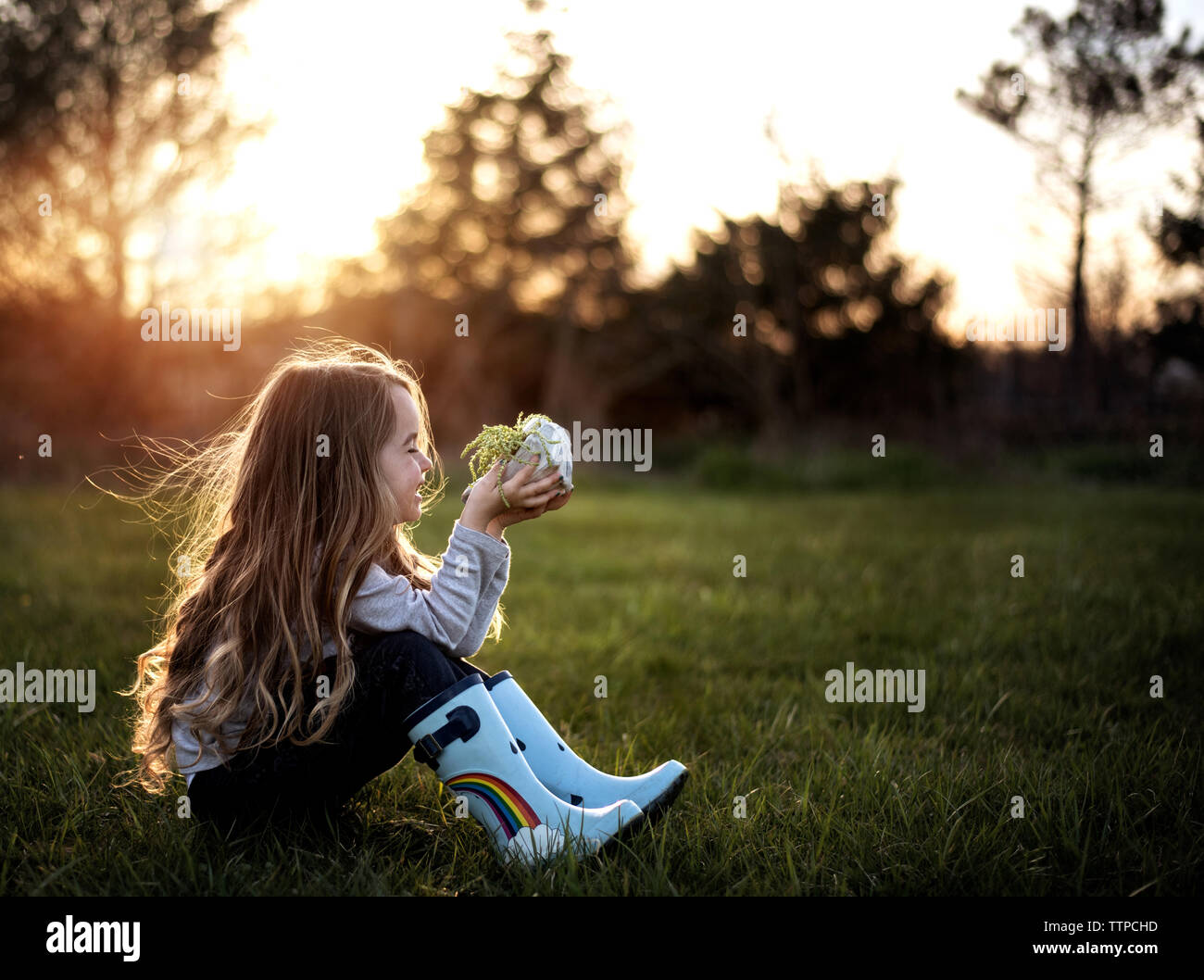 Happy young girl smiling while holding a plant au soleil Banque D'Images