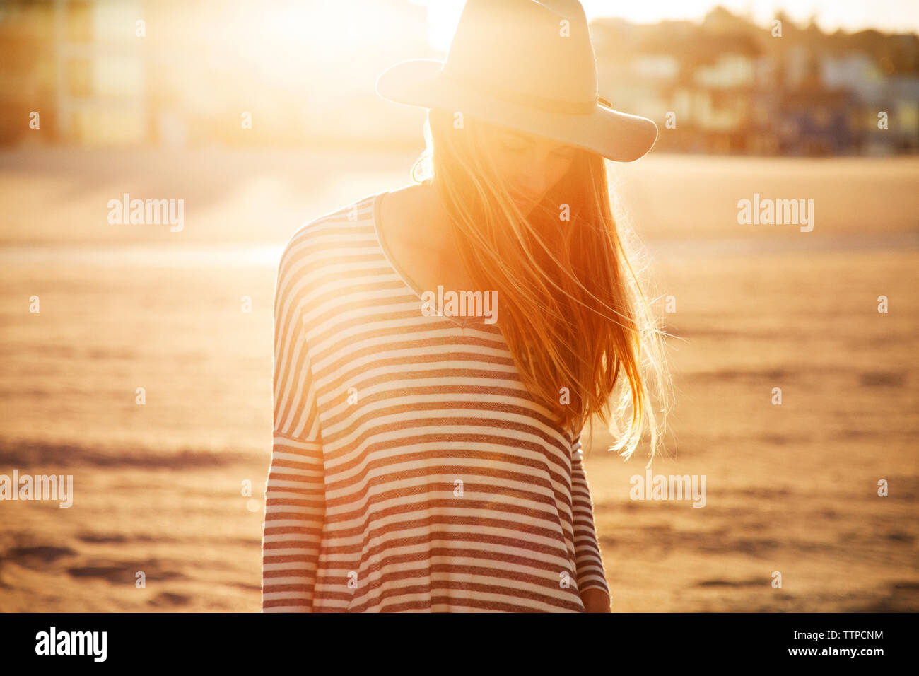 Femme debout sur la plage pendant le coucher du soleil Banque D'Images