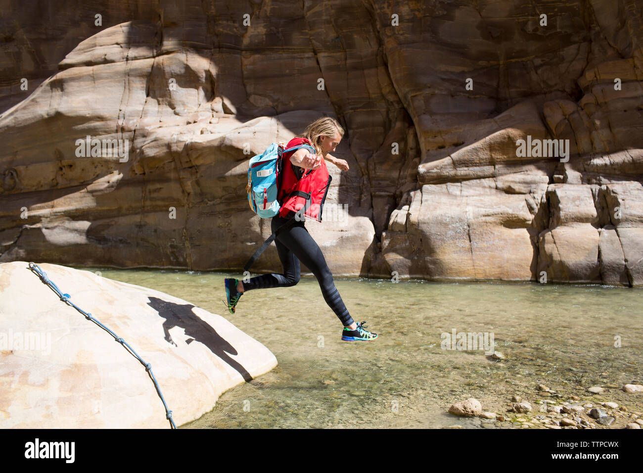 Backpacker femelle sauter dans l'eau dès les beaux jours Banque D'Images