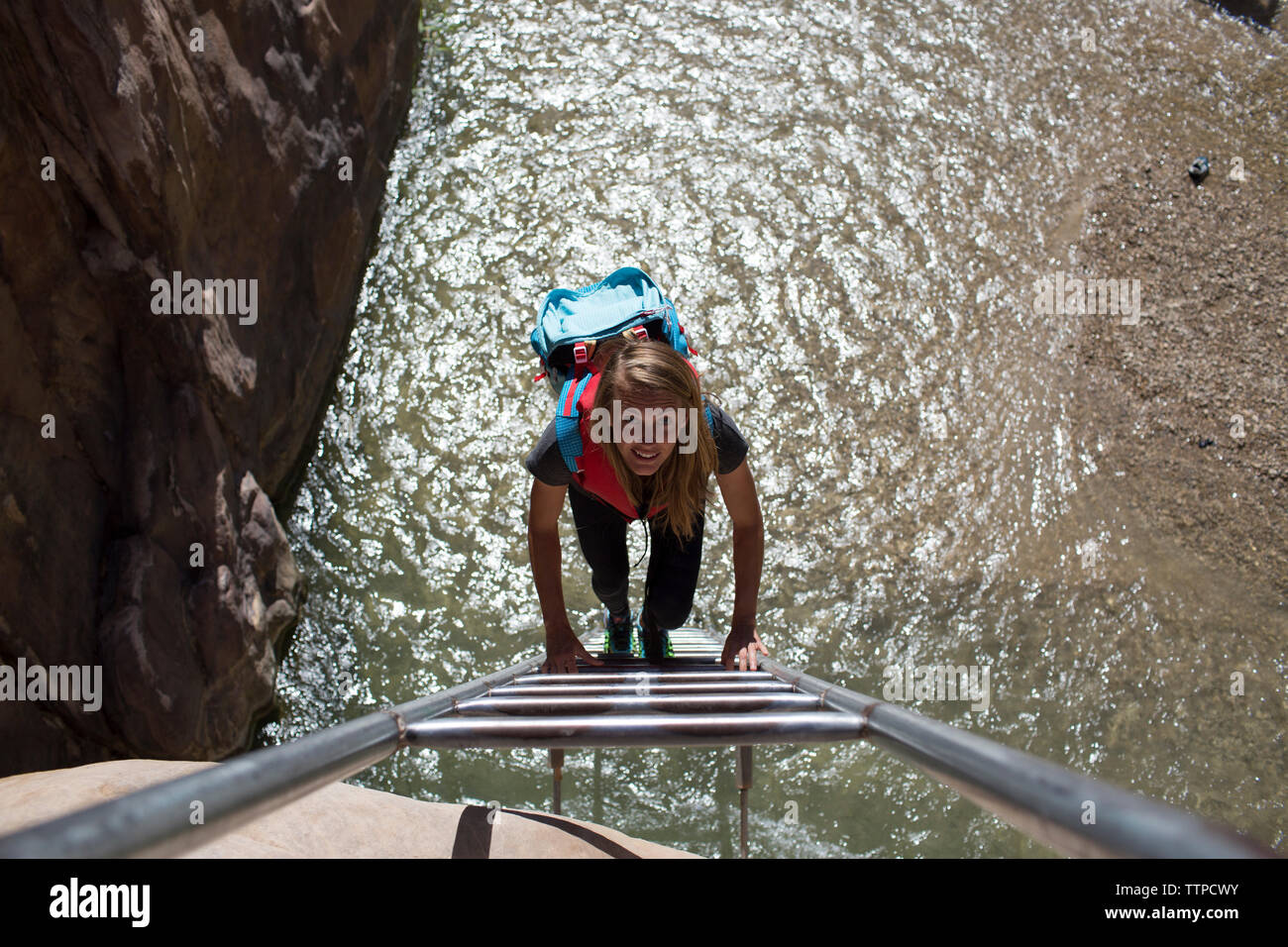 Portrait de femme backpacker climbing ladder sur sunny day Banque D'Images
