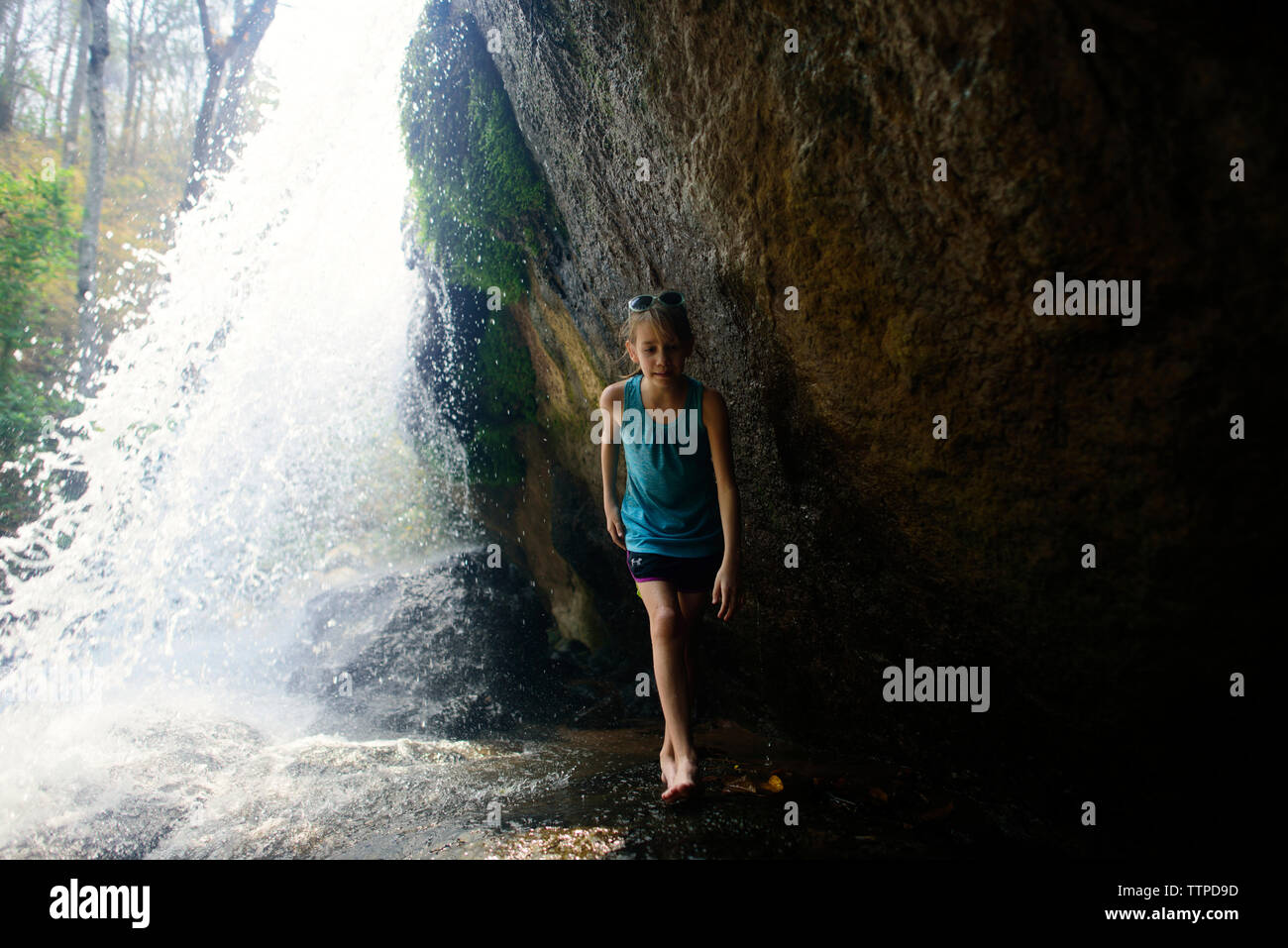 Toute la longueur de fille qui marche par des chutes d'eau Banque D'Images