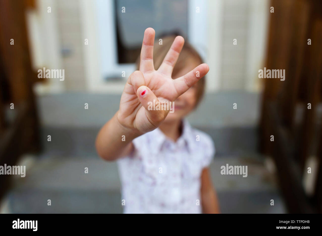 Girl montrant trois doigts tout en se tenant sur les mesures Banque D'Images