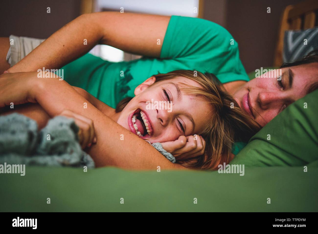 Cheerful fille couchant avec mère dormir sur le lit Banque D'Images