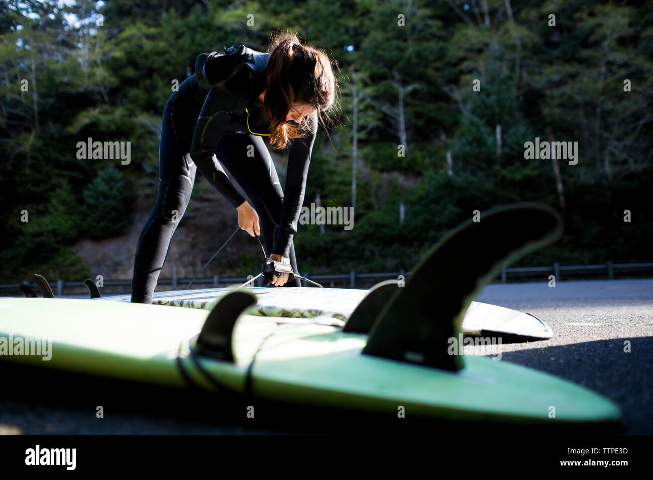 Woman wearing wetsuit préparer surfboard at beach Banque D'Images