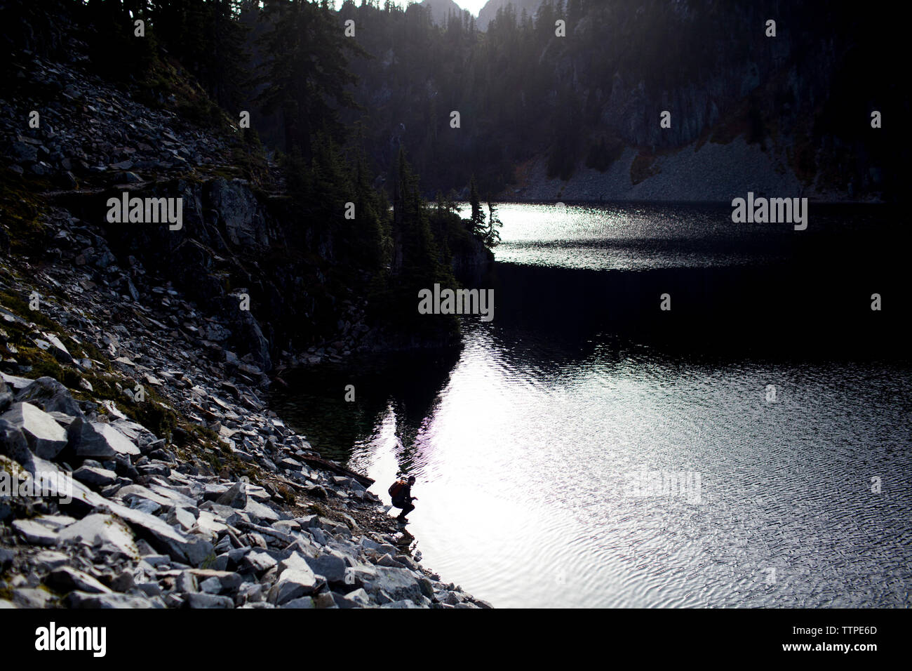 Vue lointaine du randonneur crouching by Snow Lake Banque D'Images