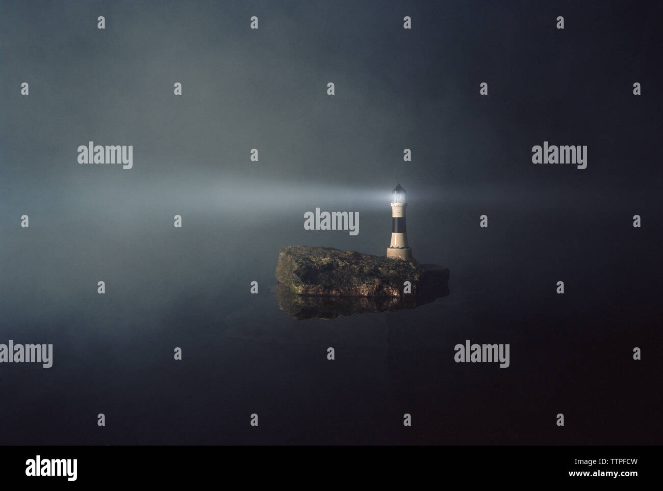 Phare allumé sur l'île contre le ciel de nuit Banque D'Images