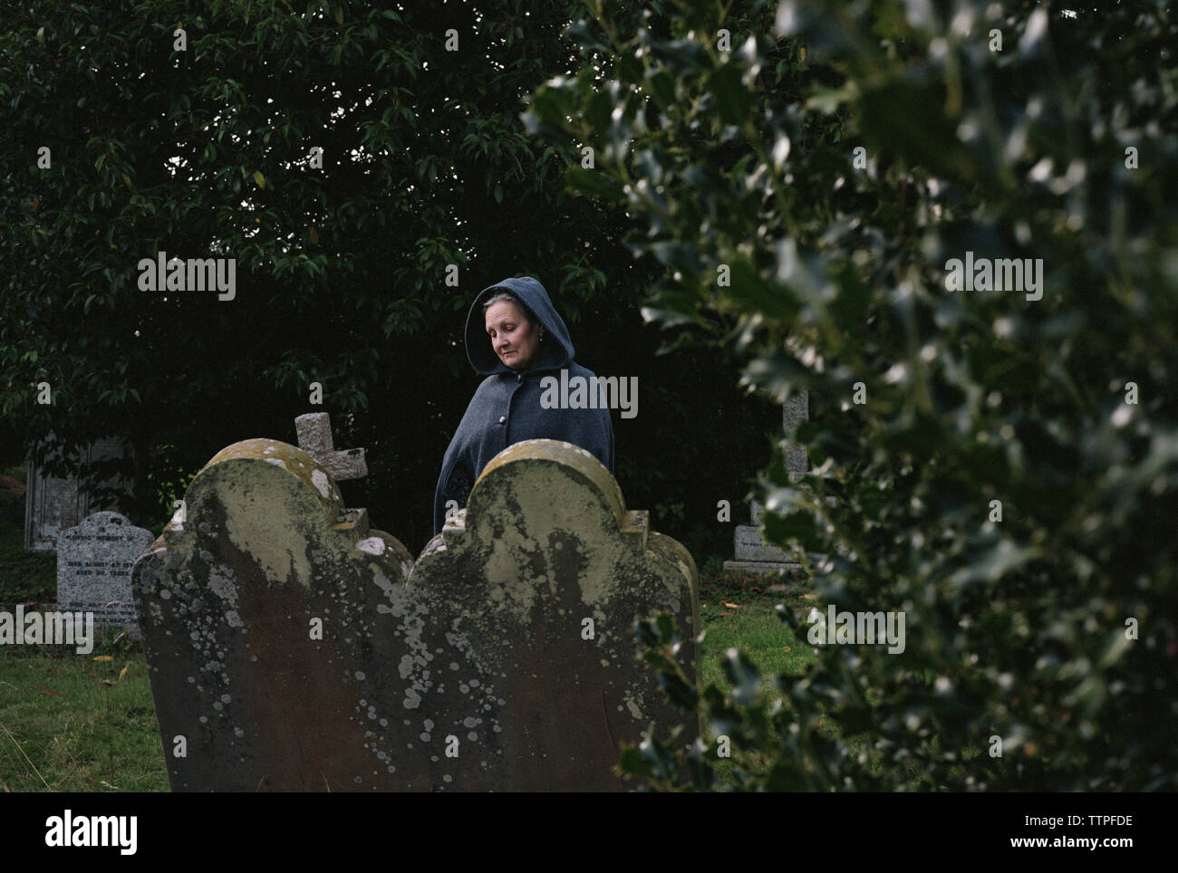 Sad woman manteau en cimetière Banque D'Images