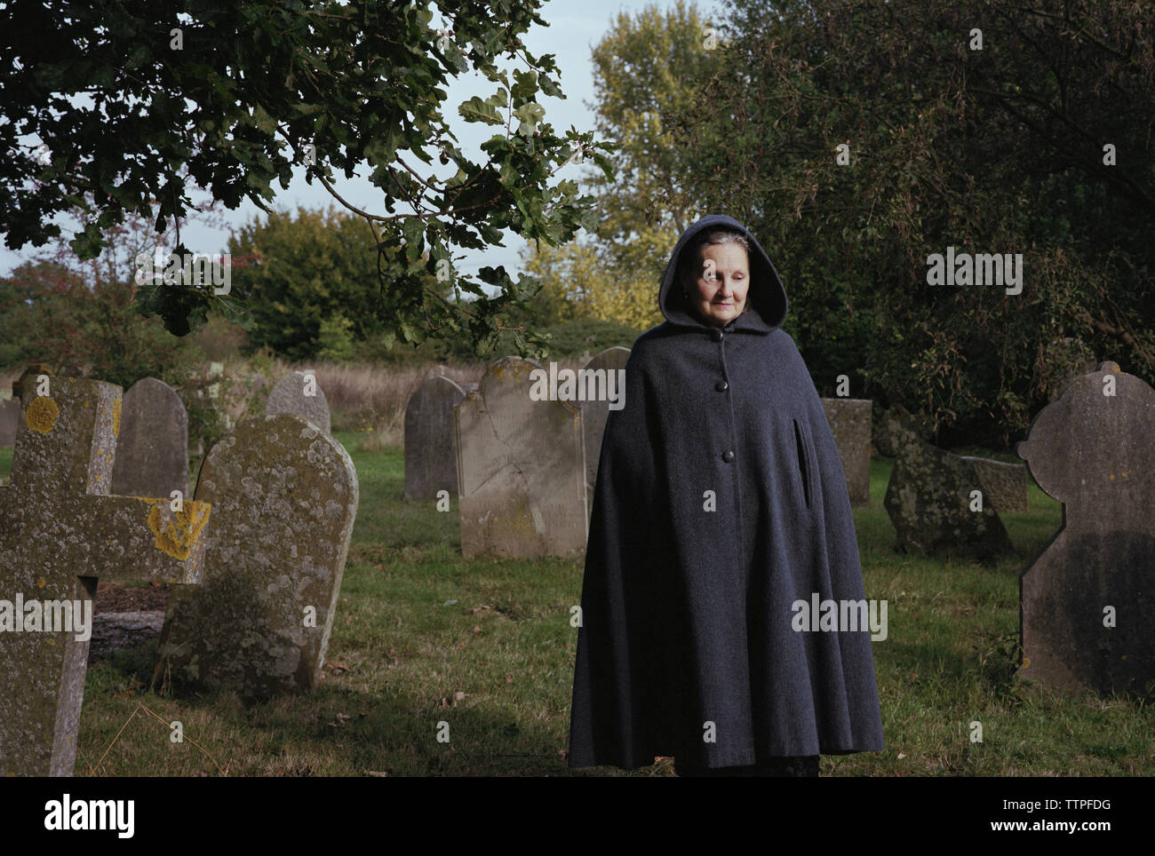 Sad woman wearing coat walking sur terrain en cimetière Banque D'Images