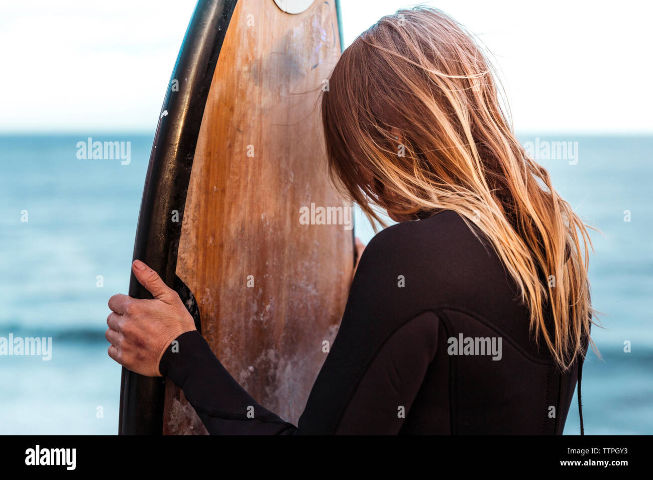 Femme wearing wetsuit tandis que with surfboard on beach Banque D'Images