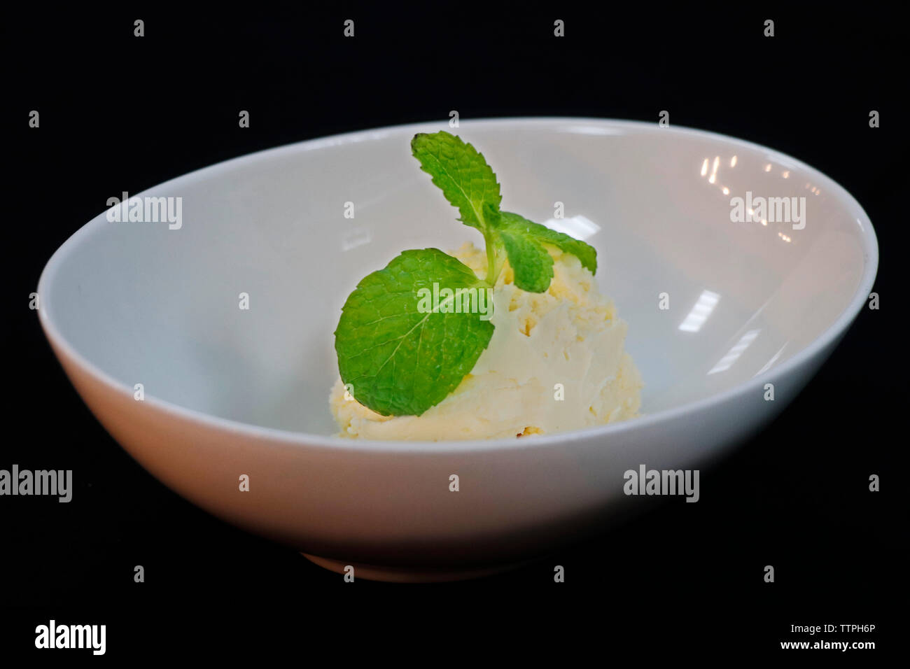 pelle à glace à la vanille au coeur de la feuille de menthe dans un bol, avec fond noir Banque D'Images