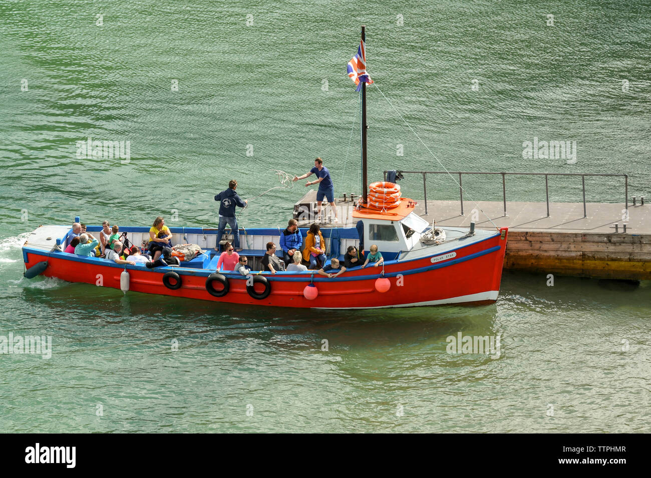 TENBY, Pembrokeshire, Pays de Galles - AOÛT 2018 : membre de l'équipage lancer une ligne à une autre personne sur la jetée comme une petite visite du port quai à Tenby Banque D'Images
