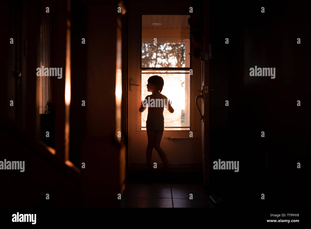 La silhouette d'un petit garçon en face d'une porte Banque D'Images