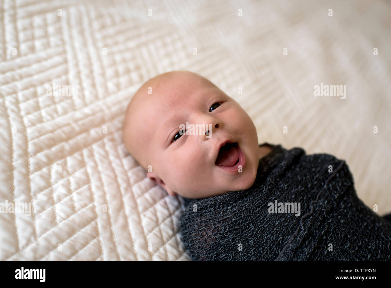 Close-up of cute baby boy laughing while lying on bed at home Banque D'Images