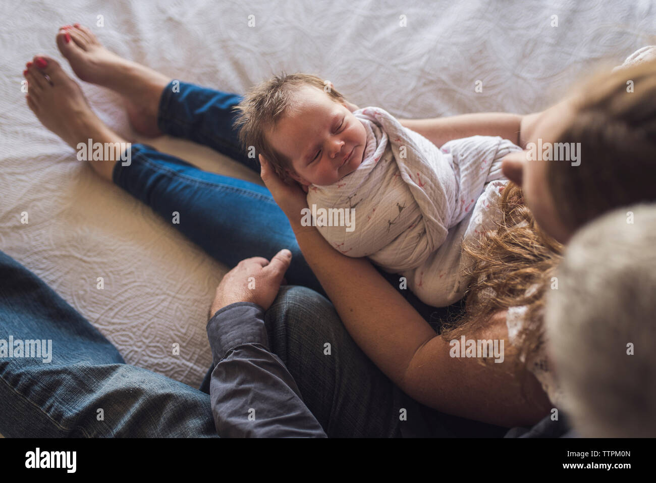 Vue de dessus de parents avec nouveau-né fille assis sur le lit à la maison Banque D'Images