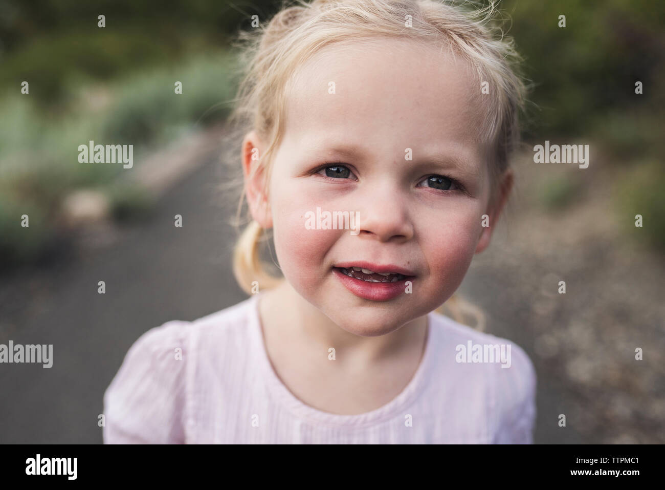 Close-up portrait of cute girl with Blonde hair standing in forest Banque D'Images