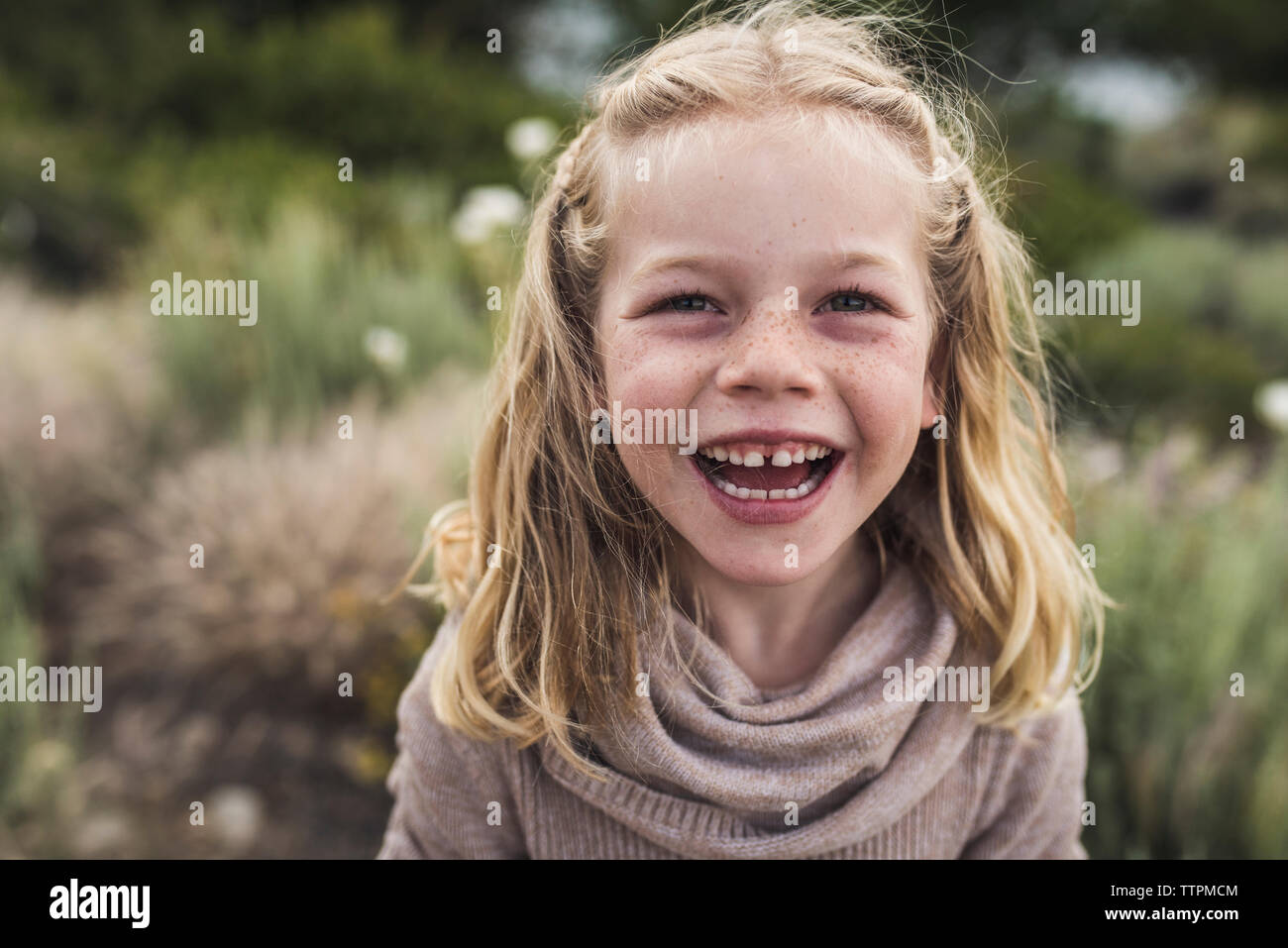 Portrait of happy girl aux cheveux blonds debout contre des plantes en forêt Banque D'Images