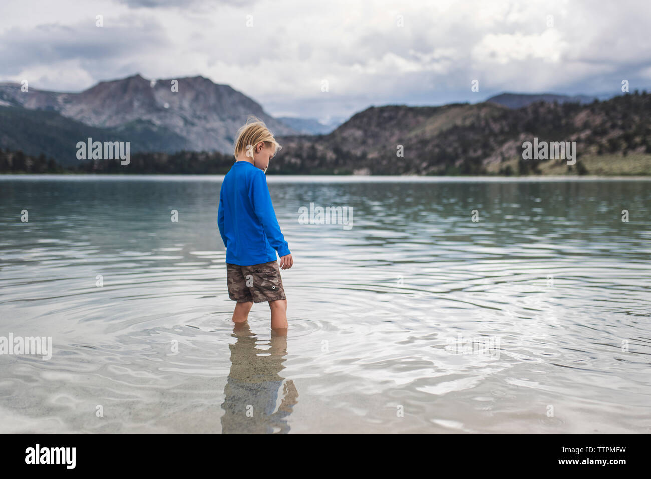 Carefree boy standing in lake montagnes contre Banque D'Images