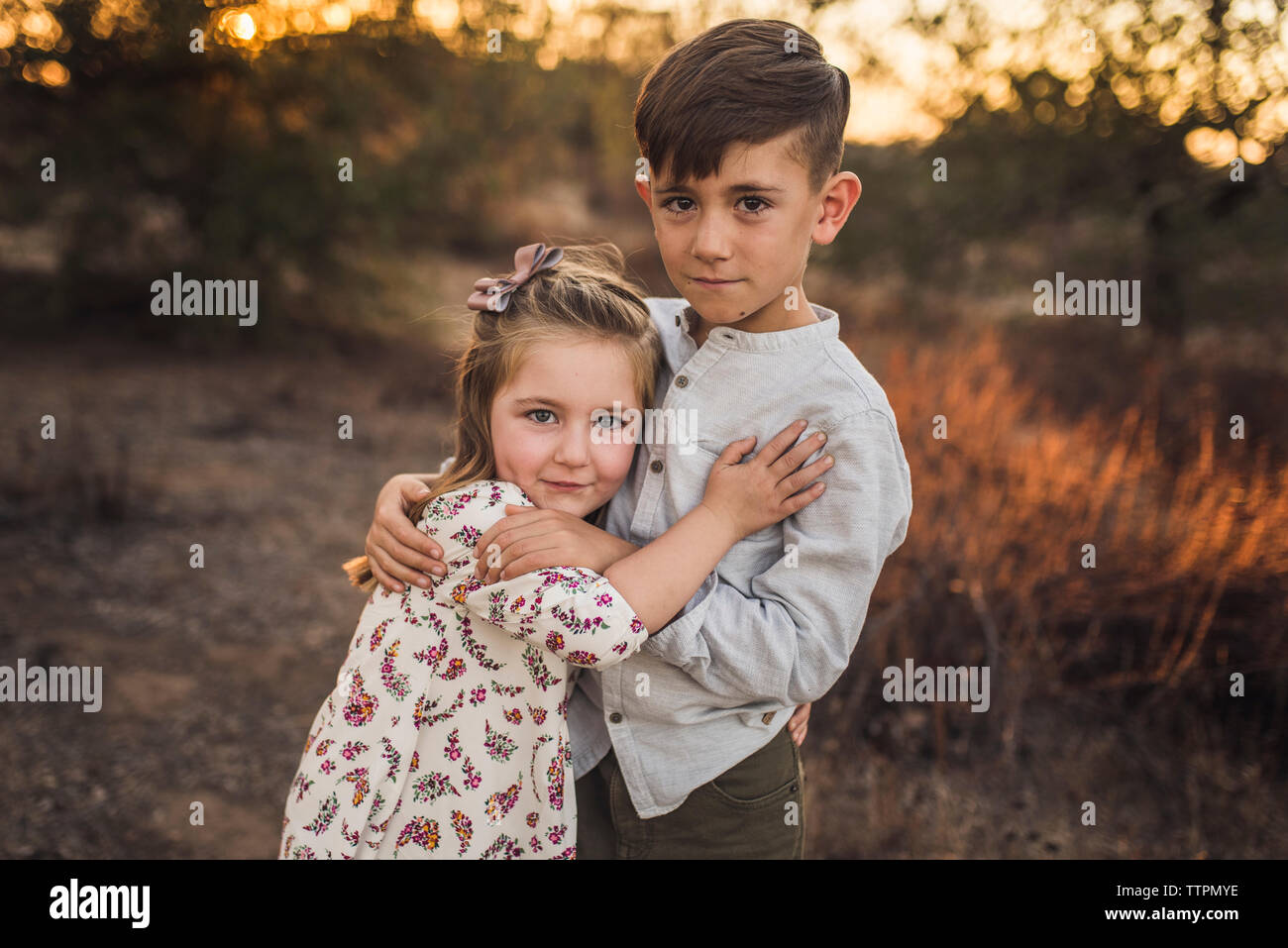 Jeune fille et boy hugging mutuellement en Californie field at sunset Banque D'Images