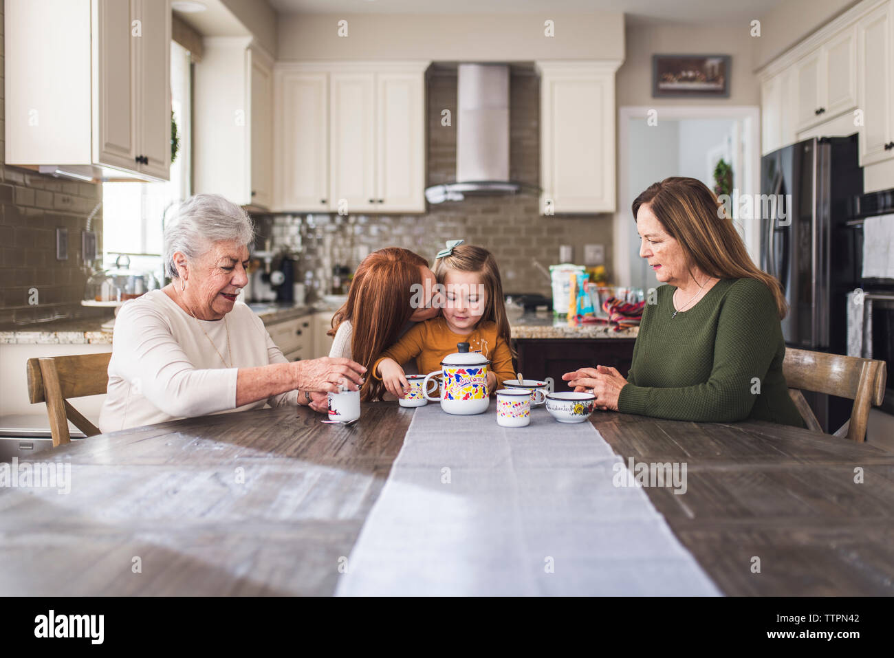 Famille de plusieurs générations de jouer avec un plateau de table de cuisine Banque D'Images