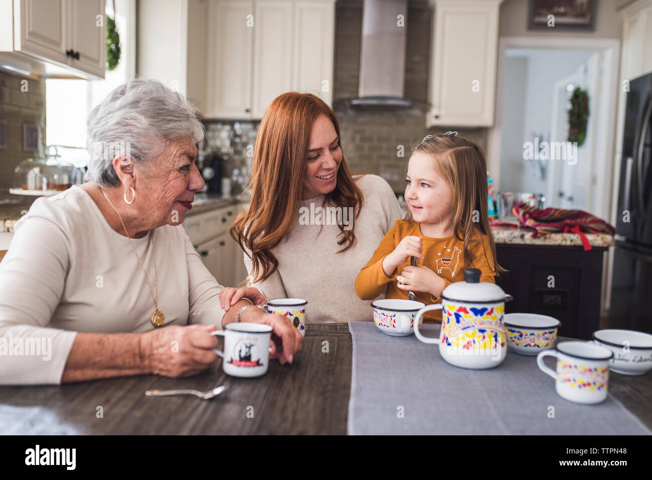 Famille de plusieurs générations de jouer avec un plateau de table de cuisine Banque D'Images