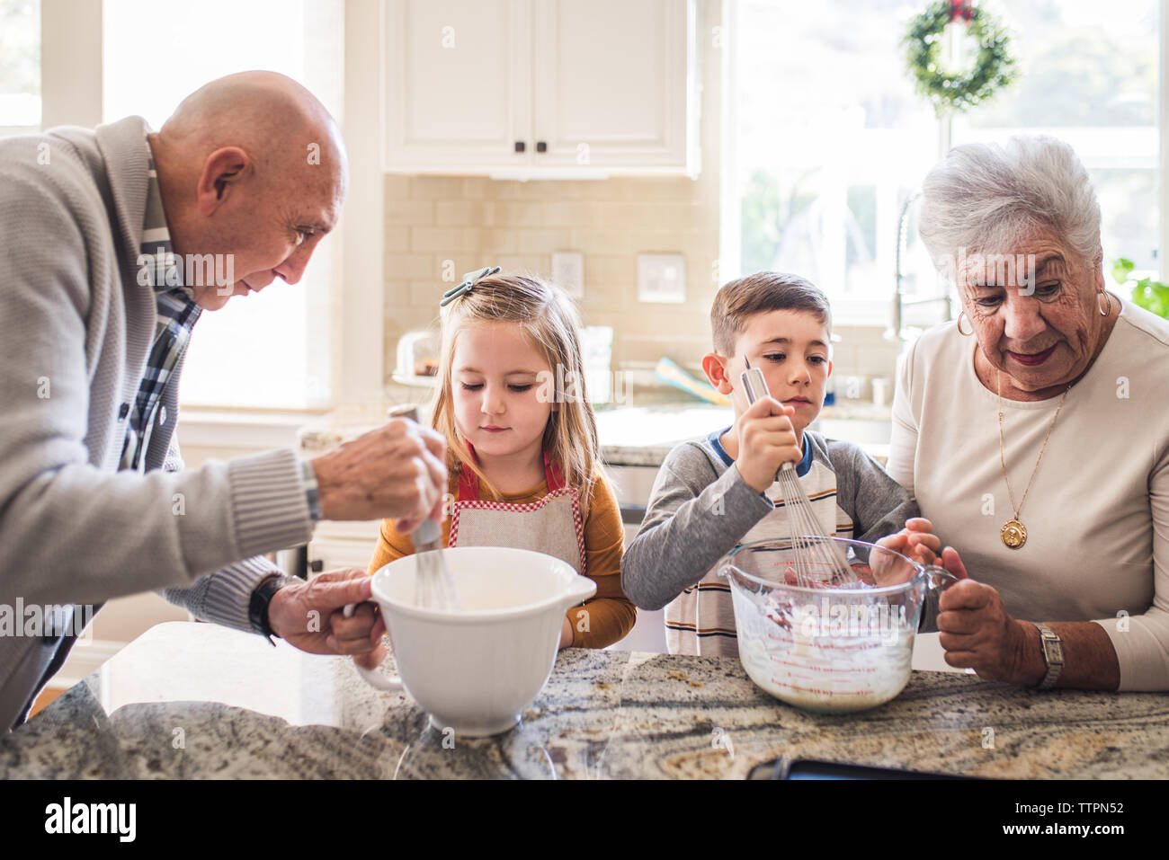Les grands-parents et petits-enfants la cuisson des crêpes pour le petit déjeuner Banque D'Images