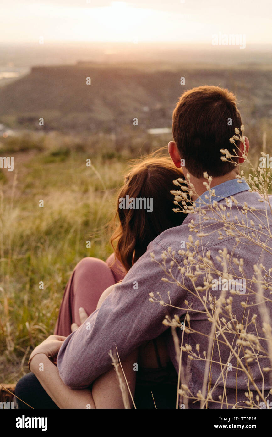 Jeune couple looking at view while sitting on field Banque D'Images