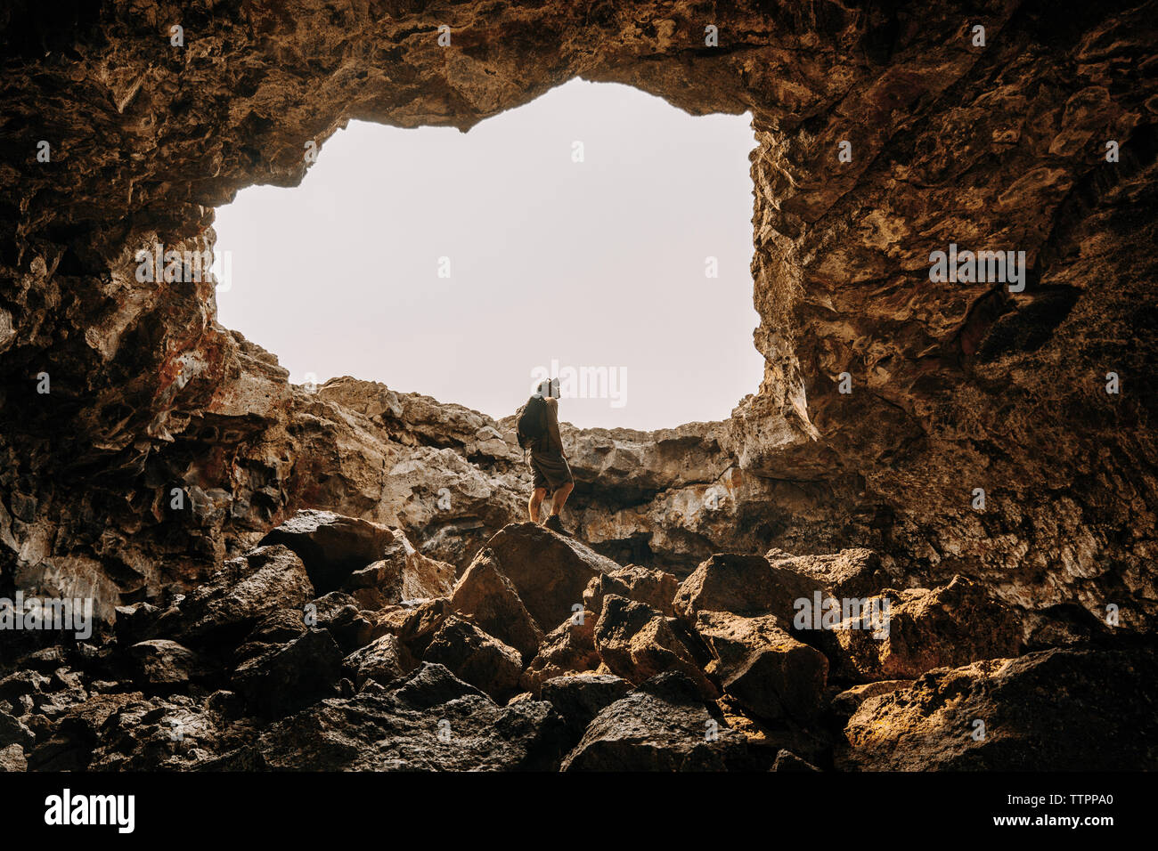 Low angle view of man de la spéléologie grotte contre ciel clair Banque D'Images