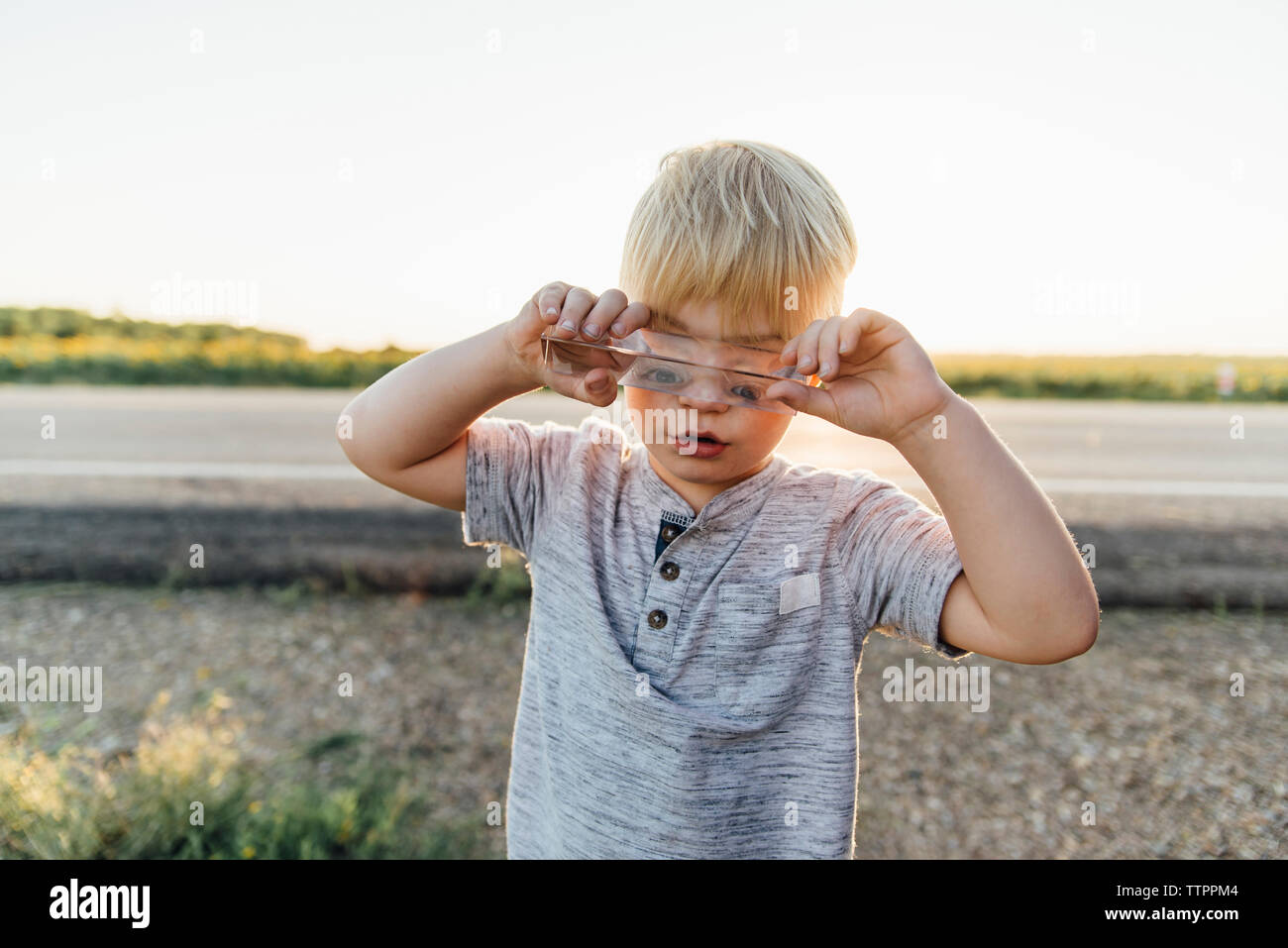 Boy Playing with toy en verre en se tenant sur le terrain Banque D'Images