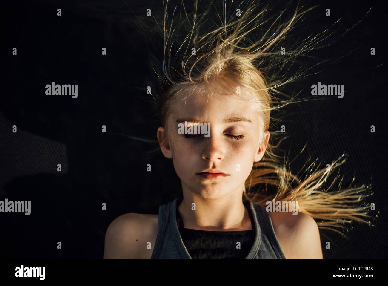 Vue de dessus de fille avec les yeux fermés et les cheveux ébouriffés au cours de journée ensoleillée Banque D'Images