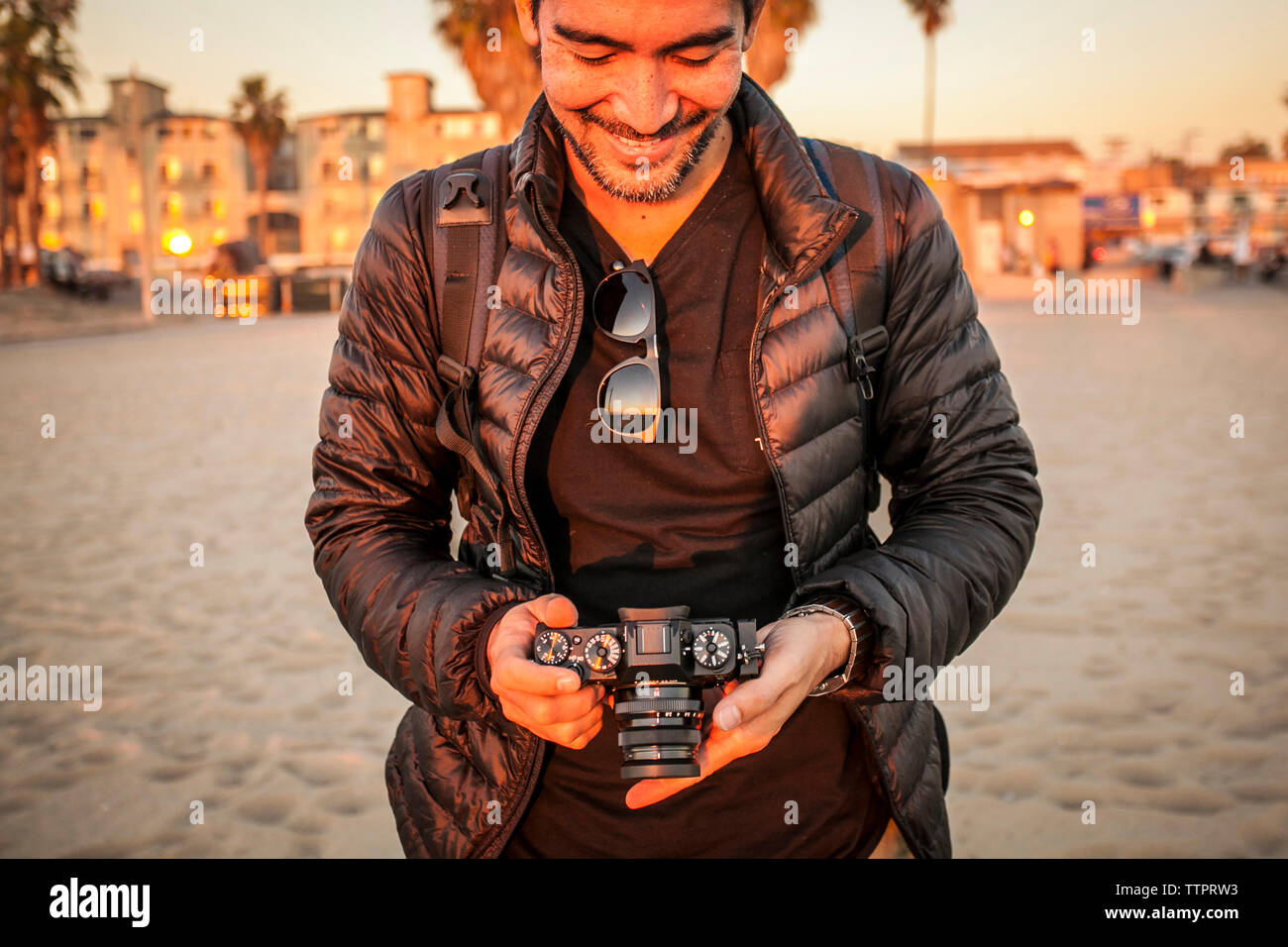 Smiling man wearing jacket en maintenant le huis clos à beach Banque D'Images